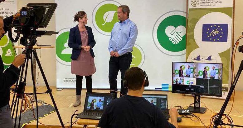 Das Moderationsteam der Veranstaltung, Saskia Helm (NUA) und Dr. Sebastian Schmidt (Bezirksregierung Münster) auf der in der NUA aufgebauten Bühne. Foto: NUA NRW