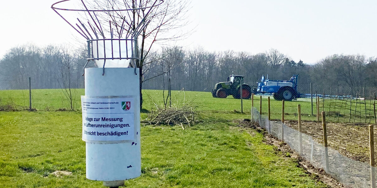 Niederschlagssammler, im Hintergrund Traktor, der ein Feld spritzt